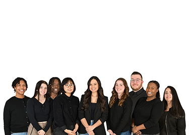 Group of eight diverse young adults standing together in black tops against a white background.