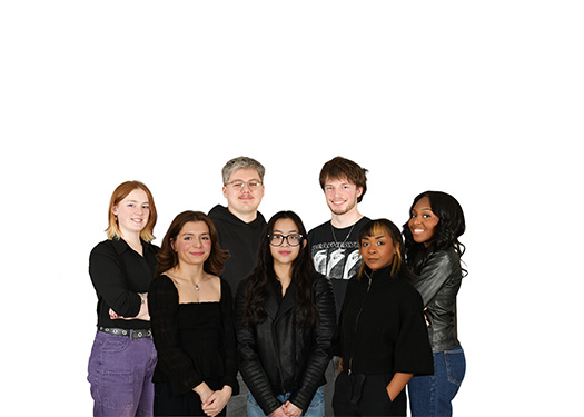 Group of seven young adults standing together and smiling, dressed casually against a white background.